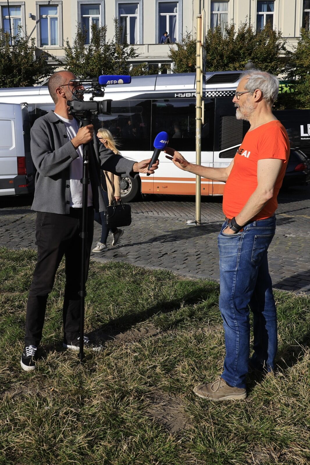 Un bénévole portant un t-shirt PauseAI est interviewé par une équipe de tournage de l'AFP.