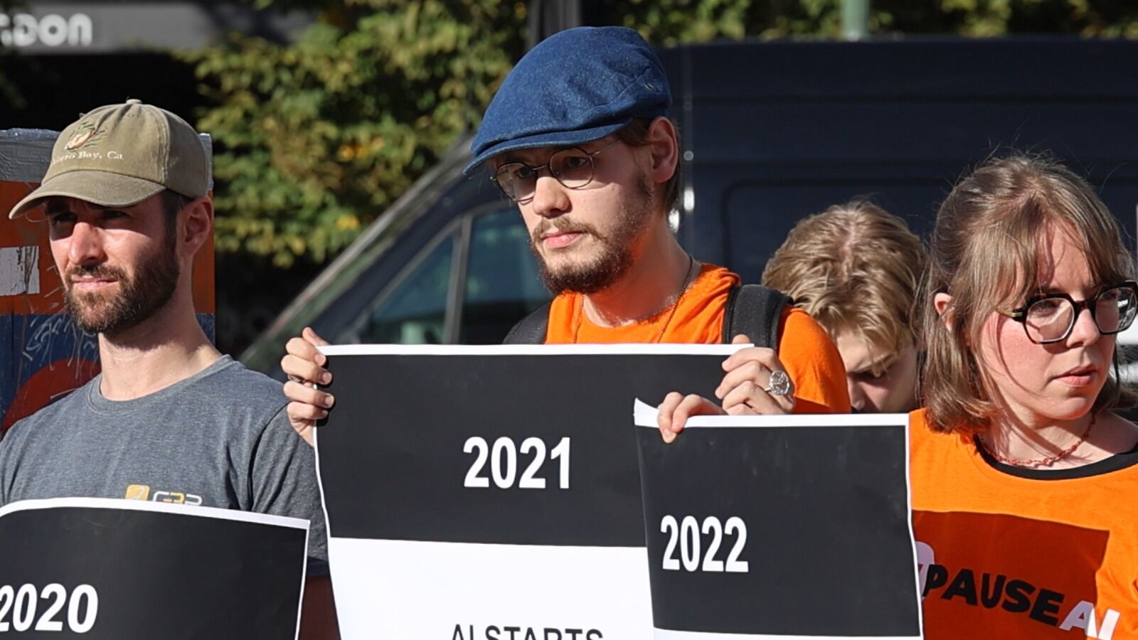 Trois bénévoles tiennent les affiches 2020, 2021 et 2022 de la chronologie de l'IA.